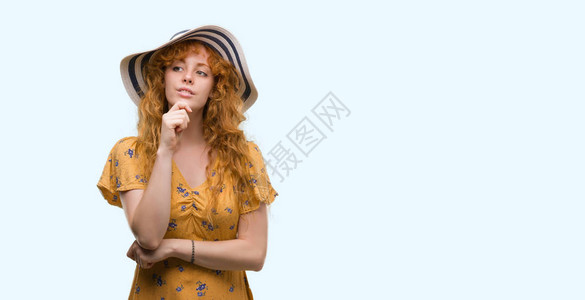 穿着暑假帽子的年轻红发女青年穿着严正的面容思考问题图片