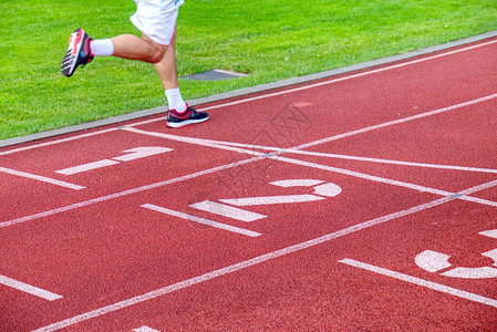 男运动员在体育场外的赛道上奔跑双腿跑图片