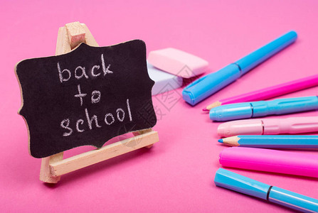 带有返校字样的小黑板和粉红色背景上亮粉色和蓝色的学习用品图片