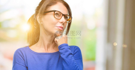 中年妇女穿着羊毛衫和眼镜思考和抬头表图片