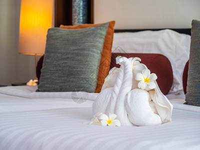 白色大象毛巾和舒适的枕头在旅馆卧室图片