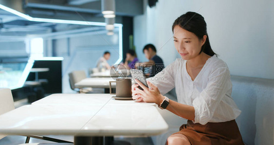 女人在咖啡店看手机图片