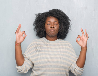 年轻的非洲裔美国大码女人穿着一件毛衣在灰色的垃圾墙上放松图片