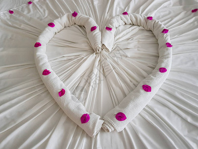 白毛巾以心脏的形式将紫花的图片