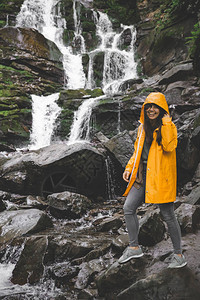 女人站在黄色雨衣上看瀑布远足概图片