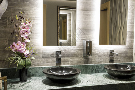 办公楼商业公共浴室的绿色特殊设计大理石台面黑色台面盆美丽的粉红色花朵镀铬水龙头金属皂液器和图片