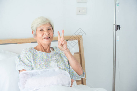 高级亚洲女病人微笑和做胜利手势的图片