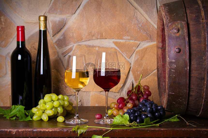 酒窖里的旧木桶旁边有葡萄的红白葡萄酒杯和酒瓶图片