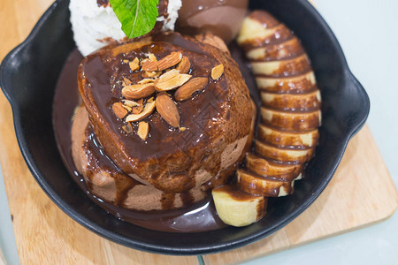 巧克力熔岩蛋糕加巧克力冰淇淋香蕉果和奶油在咖啡馆的木桌图片
