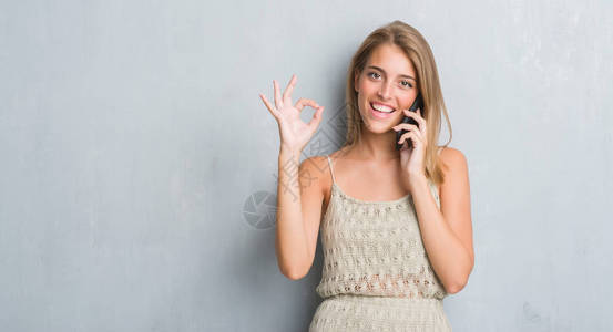 美丽的年轻美女在黑灰墙上讲着电话用手指做好手印背景图片