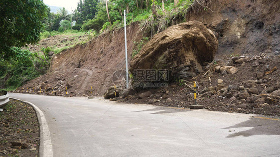 山体滑坡和山体滑坡泥土和岩石阻塞了道路被毁坏的农村道路滑坡在强大的洪水中受损倒在山上菲图片