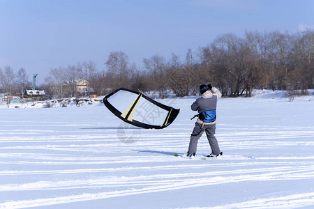 落雪者用风筝捉风站在冰冻池塘的冰图片