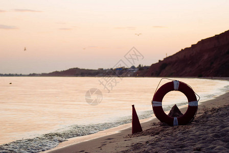 古老的红色传声机和一个生命保护器日落时沙滩海洋救图片