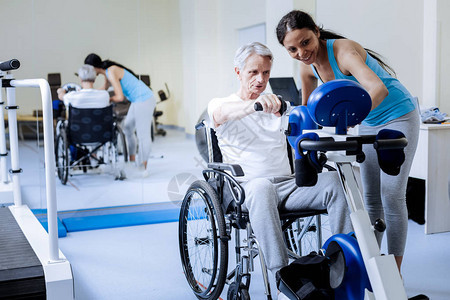 积极乐观的轮椅老人尝试在康复中心锻炼的新机会背景图片