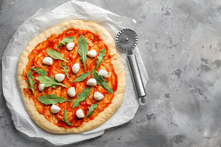 生比萨配番茄酱和灰色背景的配料图片