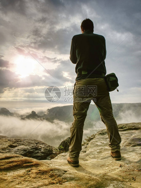 自然摄影师在岩石高峰用镜像照相机拍摄照片图片