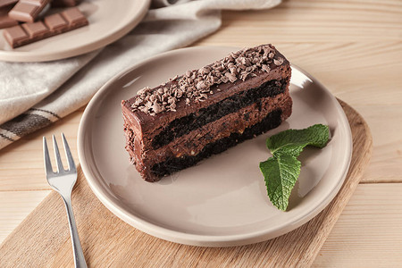 在木板上配一块美味巧克力蛋糕的盘子图片