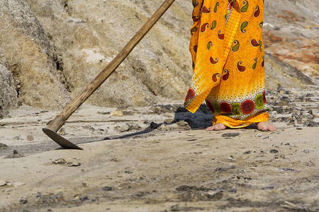 一个穿着民族光亮裙子的女人和一头原始的母蹄试图耕种干燥图片