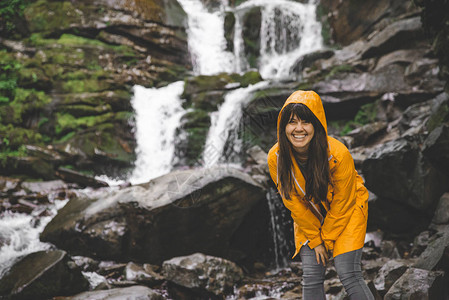 女人站在黄色雨衣上看瀑布远足概图片