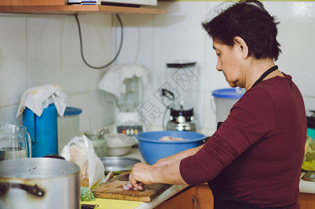 老年妇女从厨房的新鲜蔬菜中准备健康的家庭食品图片