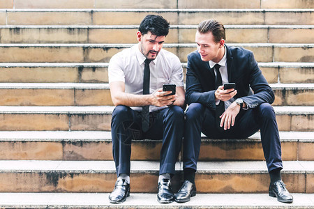 两位坐着放松的商人使用智能手机操作和检查社会应用程序技术图片