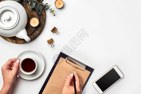 一个女人手在空书笔记日记传播模型顶视图工作室上写字杯咖啡休息时间笔记本中用于博客条目的空白间图片