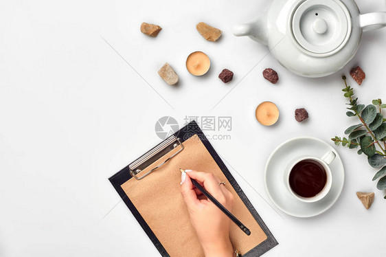 一个女人手在空书笔记日记传播模型顶视图工作室上写字杯咖啡休息时间笔记本中用于博客条目的空白间图片
