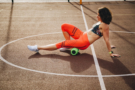 美丽的苗条健壮的高加索女运动员利用泡沫滚绿野地街头锻炼运动来消除疼痛伸展和按摩肌肉图片