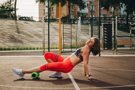 美丽的苗条健壮的高加索女运动员利用泡沫滚绿野地街头锻炼运动来消除疼痛伸展和按摩肌肉图片