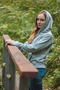 红长头发的女孩旅行者站在森林桥上图片