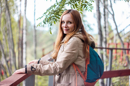 红长发女孩旅行者站在森林桥上图片