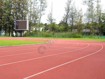 运动场上的红色跑步机绿草和阳光背景图片