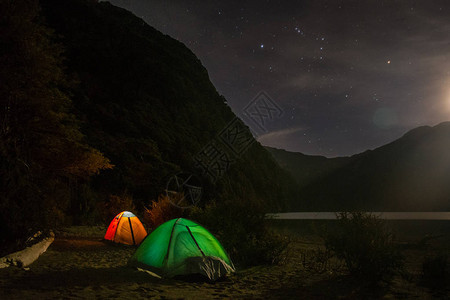 巴塔哥尼亚夜间露营的两个帐篷湖边露营地帐篷从内部照亮图片