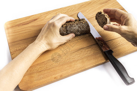 女人用刀子切一小块全餐面包木板上图片