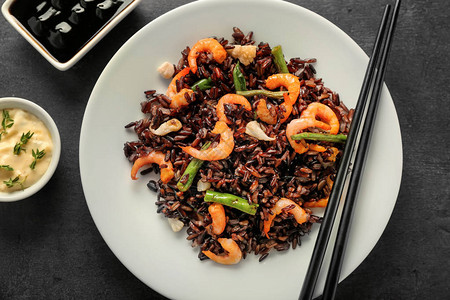 黑桌上放着米饭虾和蔬菜的盘子图片