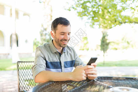 中年男在花园餐桌上使用手机在社交网络中发图片