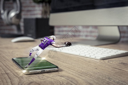 穿着紫色制服的足球运动员在木桌上玩着全屏手机观看按需概念的足球比图片