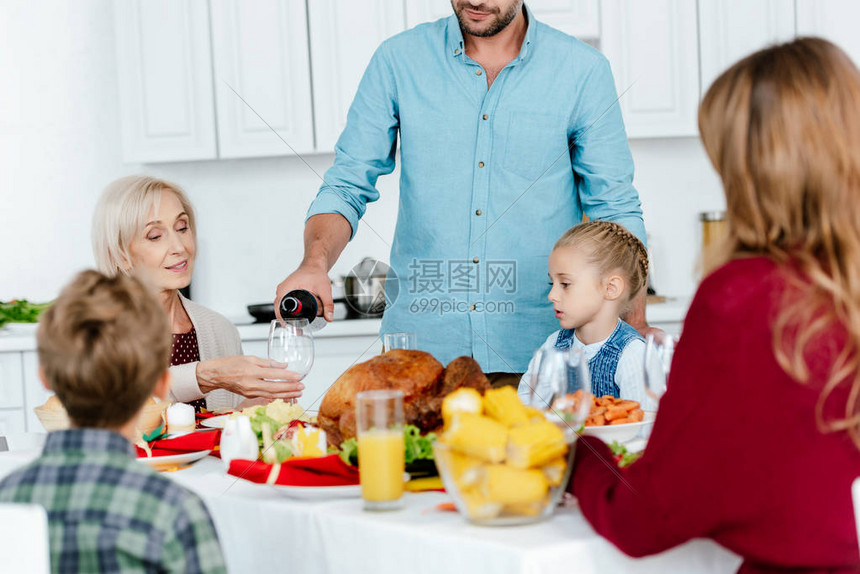 当家人在餐桌上用烤火鸡庆祝感恩节时将红酒倒入玻璃中图片