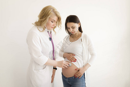 医生在怀孕的肚子里听婴儿的心跳医生在工作中使用听诊器一图片