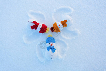 三个戴着帽子和围巾的滑稽雪人正躺在雪地上图片
