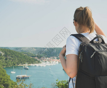 女游客背着包看着湖边的城市图片