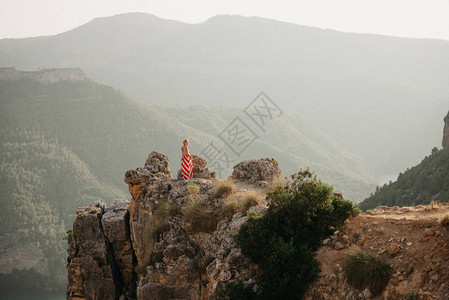 穿红白裙子的时髦金发女郎在峡谷悬崖顶上摆姿山在图片