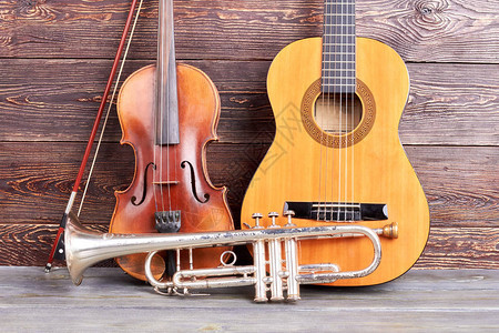 木制背景的旧乐器古典小提琴小号吉他图片