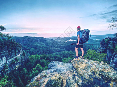 专业摄影师用三脚架在悬崖上思考日出中的梦幻景观下面美丽图片