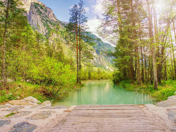 尖利岩石之间平静的蓝湖山峰与乌云相触及戏剧天空美妙的山谷远图片