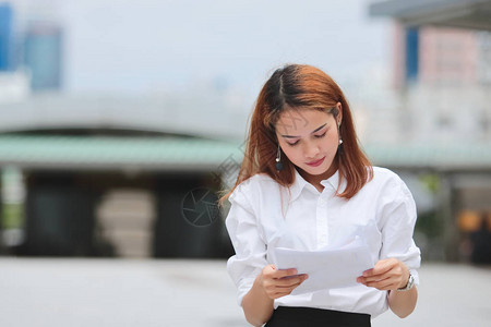 自信的亚洲年轻女商人坐在户外分析图图片