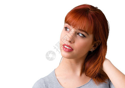 年轻红发女孩有怀疑和混淆脸部表情的图片