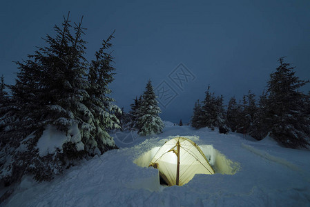 冬天的山帐篷极端的旅游徒步旅行夜景与白雪皑的森林图片