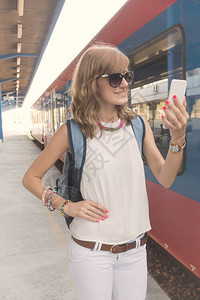 在复古火车站使用手机的可爱小女孩图片