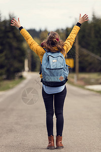 女孩张开双臂走在空荡的路上图片